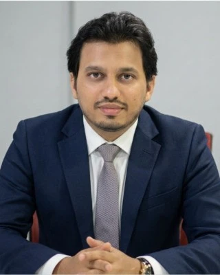 Mohammed Arfan Yusuf in a navy suit, seated at a meeting table